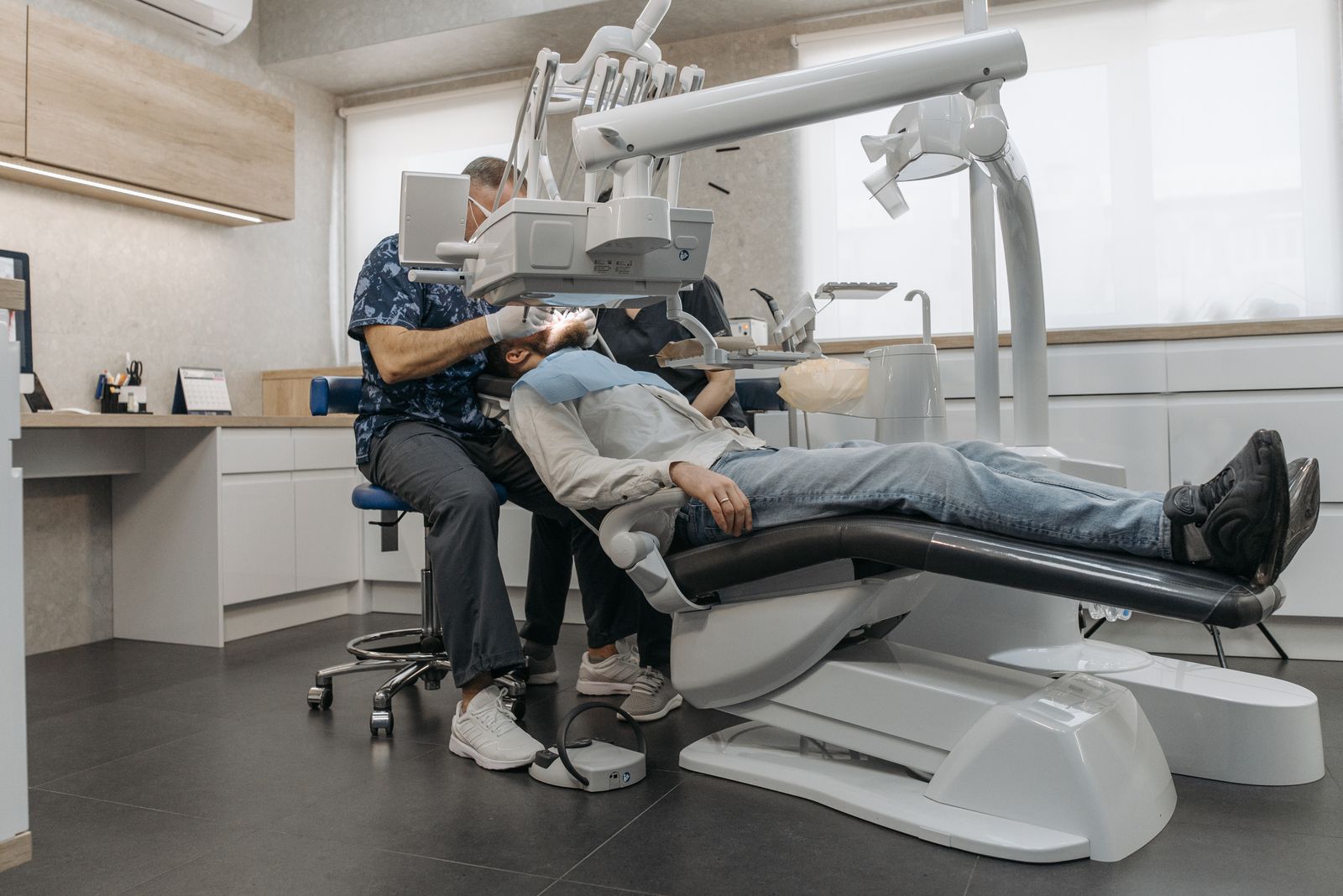 A dentist examines a patient using advanced dental equipment in a modern clinic setting