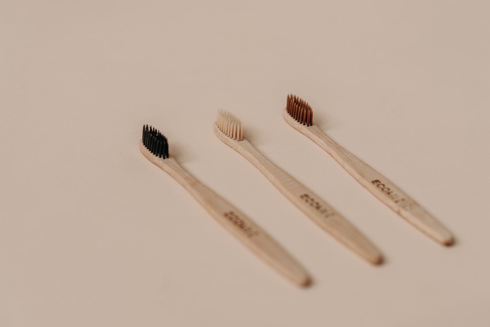 Set of eco-friendly bamboo toothbrushes on a neutral background
