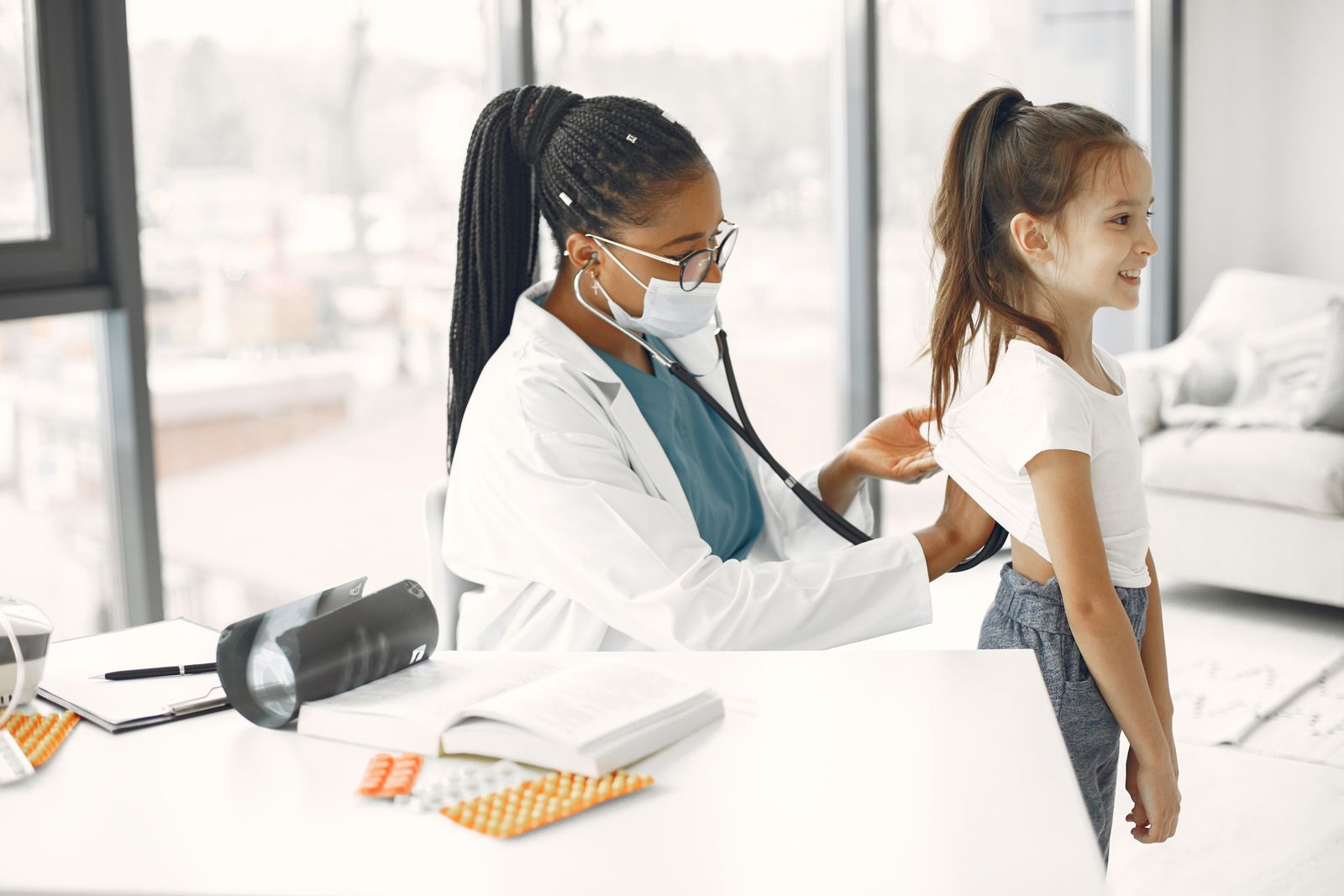 A female doctor gives a health check-up to a child in a bright clinic