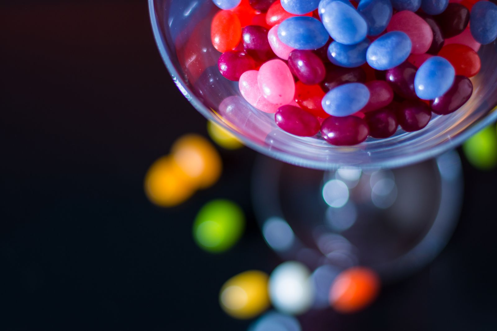 Vibrant close-up of colorful jelly beans inside a cocktail glass with bokeh effect