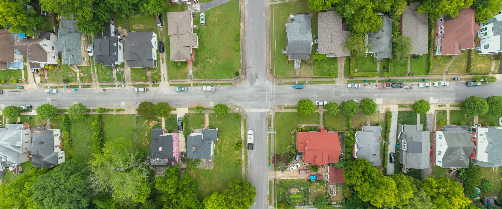 Aerial photo capturing an intersection in a suburban neighborhood with houses and greenery