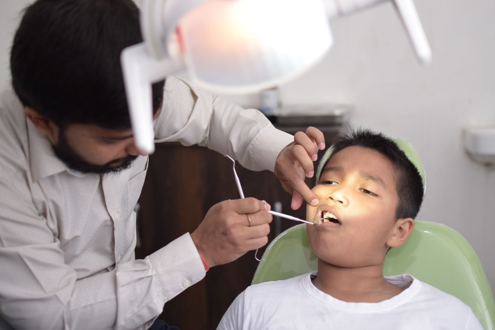 A dentist checks a child's teeth in a well-lit dental clinic, focusing on oral care