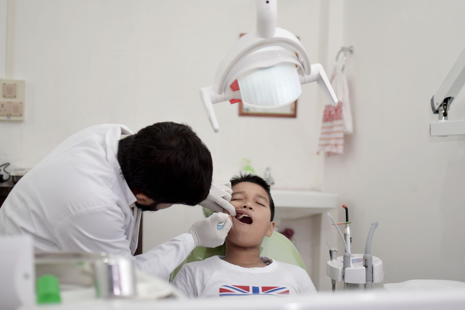 A young boy is receiving a dental checkup from a dentist wearing gloves in a clinic