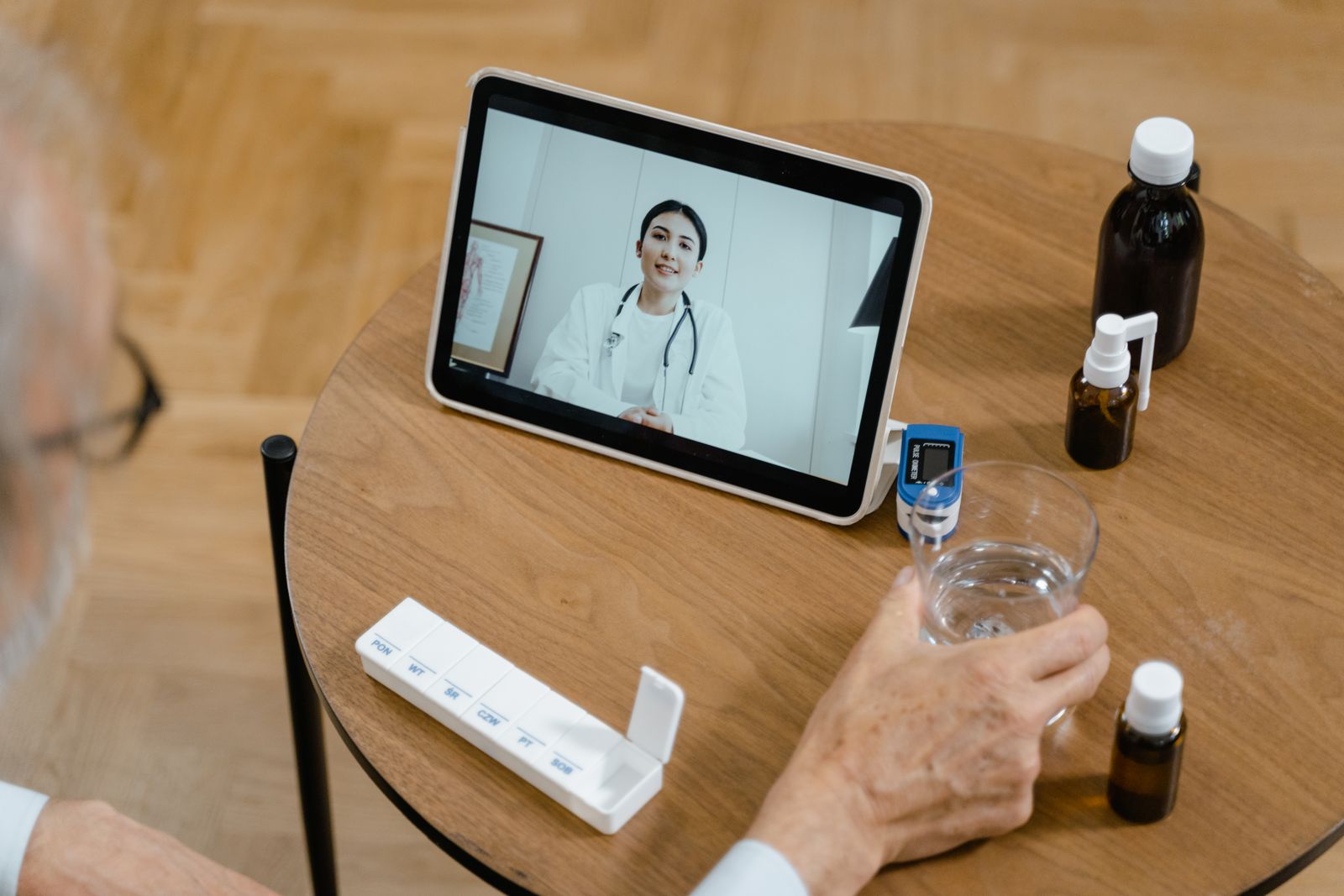 Senior adult having a virtual doctor consultation on a tablet with medications on the table