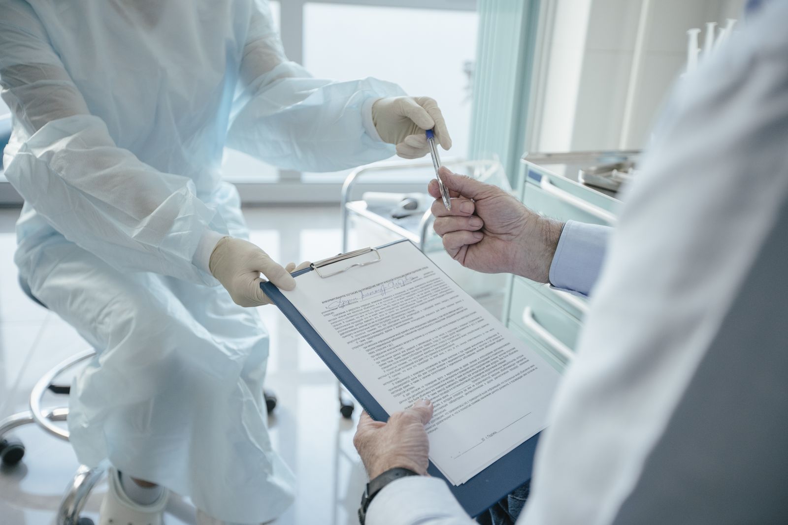A doctor hands a clipboard to a patient for signature, highlighting medical professionalism