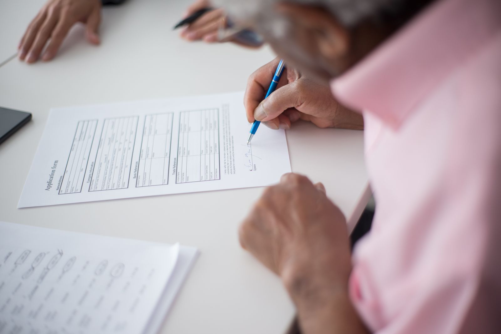 Elderly man signing important business document at desk in office setting