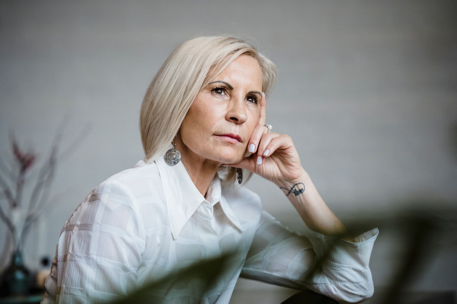 Portrait of a well-dressed senior woman lost in pensive thought indoors