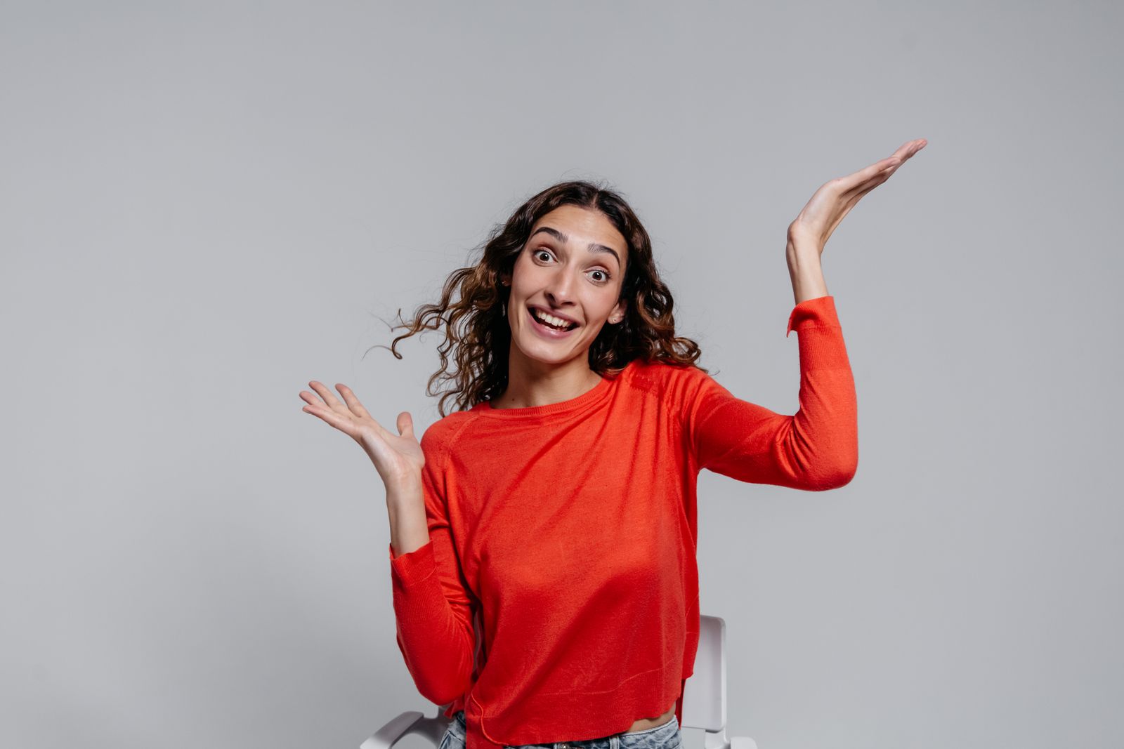 Portrait of a joyful young woman in a red sweater with an enthusiastic expression